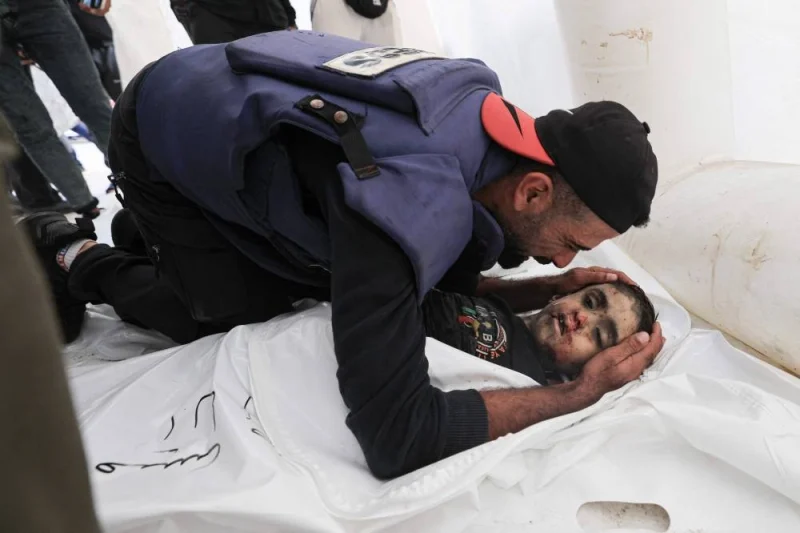 Palestinian cameraman Mohammed Alaloul bids his son farewell after he was killed in an Israeli strike on the Al-Maghazi refugee camp in Deir Balah in the central Gaza Strip, in front of al-Quds hospital in the same city on Sunday. AFP