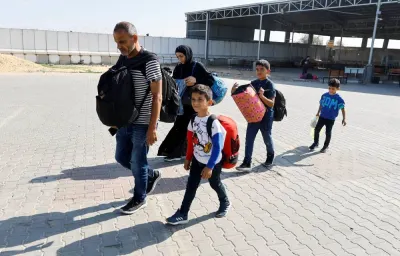 Family members carry their luggage as Palestinians, including foreign passport holders, wait at Rafah border crossing in the southern Gaza Strip.