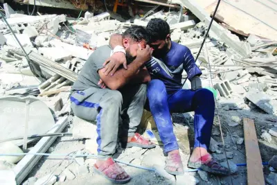 
Palestinians mourn as they sit on the rubble of a building in Gaza City’s Shati refugee camp, yesterday. 