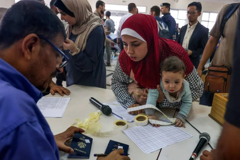 Civilians leaving display their documents as dual national Palestinians and foreigners prepare to cross the Rafah border point with Egypt, in the southern Gaza Strip, on Thursday. AFP