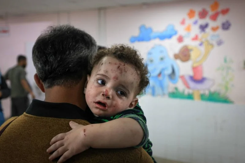 A man holds one of the injured children of Palestinian cameraman Mohammed Alaloul following an Israeli strike on the Al-Maghazi refugee camp in Deir Balah in the central Gaza Strip, at the al-Quds hospital in the same city on Sunday. AFP