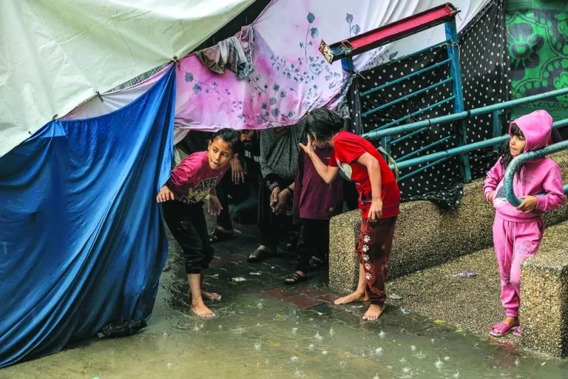 
Children take shelter from the rain under a tent at a school run by the UN Relief and Works Agency for 
Palestine Refugees in the Near East (UNRWA), in Rafah in the southern Gaza Strip, yesterday. 