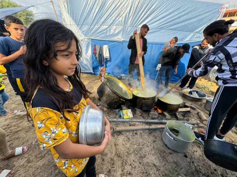 Children wait while displaced Palestinians, who fled their houses due to Israeli strikes, cook lentil soup on a rainy day at Nasser Hospital in Khan Younis in the southern Gaza Strip, Tuesday. REUTERS