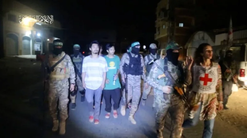 Hostages handed over by Hamas to members of the International Committee of the Red Cross in an unknown location in the Gaza Strip, in this screengrab taken from video released Sunday. Hamas Military Wing/Handout via REUTERS