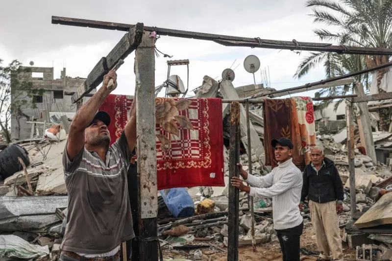 Palestinian men set up a structure amid the destruction caused by Israeli strikes in the village of Khuzaa, east of Khan Yunis near the border fence between Israel and the southern Gaza Strip on Monday, amid a truce in battles between Israel and Hamas. AFP