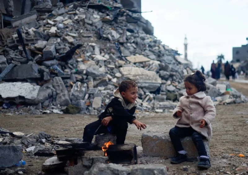 Palestinian children sit by the fire next to the rubble of a house hit in an Israeli strike during the conflict, amid a temporary truce between Hamas and Israel, in Khan Younis in the southern Gaza Strip, on Monday. REUTERS