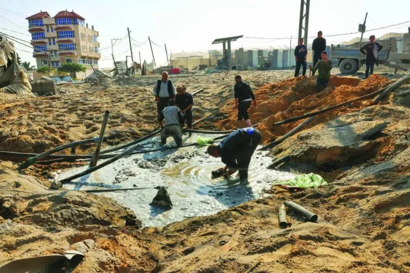 Palestinian workers repair a damaged water pipe following an Israeli airstrike on the main road between Rafah and Khan Yunis on the 
southern Gaza Strip, yesterday.