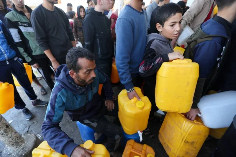 Palestinians wait to fill containers with water, in Khan Younis, in the southern Gaza Strip, on Monday. REUTERS
