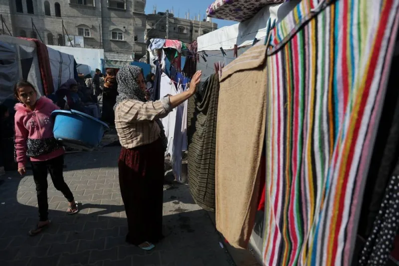 A woman stands in front of towels as Palestinians, who fled their houses amid Israeli strikes, shelter at a United Nations-run school, in Khan Younis, in the southern Gaza Strip, on Monday. REUTERS