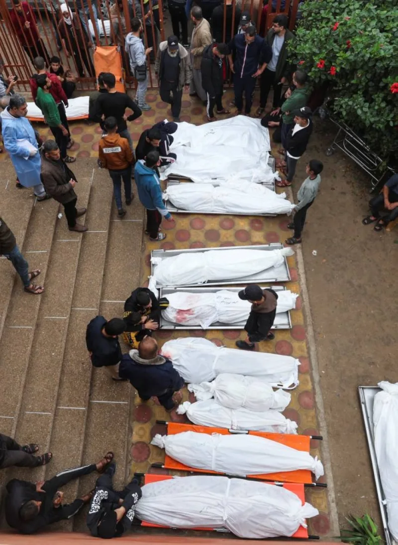 People stand near bodies of Palestinians who were killed during Israeli strikes on Ma&#039;an school east of Khan Younis, at Nasser hospital, on Tuesday. REUTERS