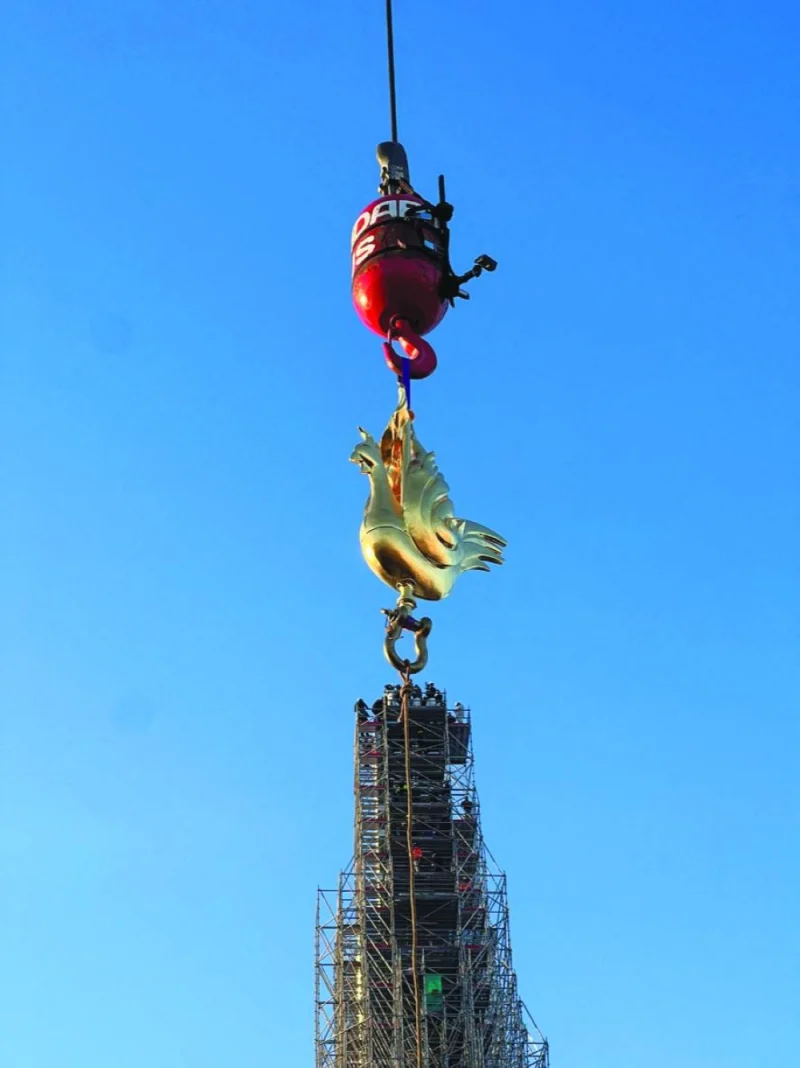 
A crane raises the new rooster to install it at the top of the spire of the Notre-Dame de Paris Cathedral, which was ravaged by a fire in 2019 that sent its spire crumbling down, in Paris, yesterday. (Reuters) 