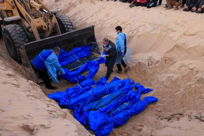 The shrouded bodies of Palestinians killed in northern Gaza, that were taken and later released by Israel, are buried in a mass grave in Rafah, on the southern Gaza Strip, on Tuesday. AFP