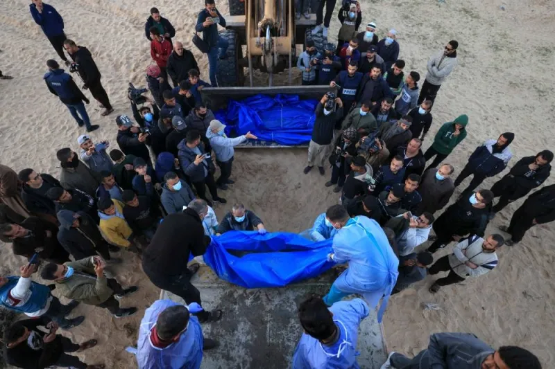 The shrouded bodies of Palestinians killed in northern Gaza, that were taken and later released by Israel, are unloaded from a container to be buried in a mass grave in Rafah, on the southern Gaza Strip, on Tuesday. AFP