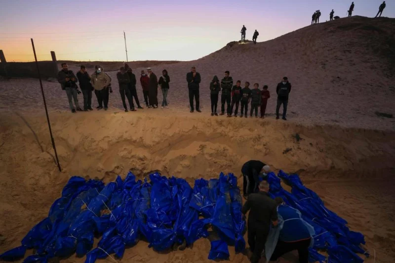 People look on as the shrouded bodies of Palestinians killed in northern Gaza, that were taken and later released by Israel, are buried in a mass grave in Rafah, on the southern Gaza Strip on Tuesday. AFP