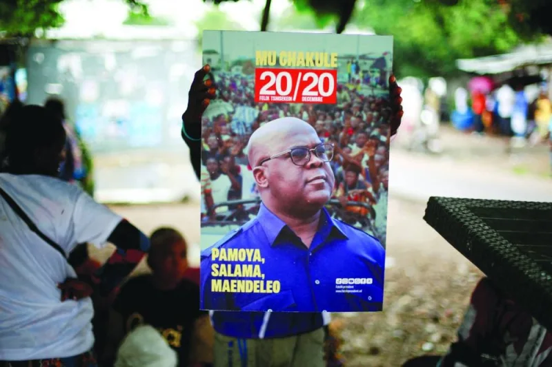 
This picture taken on December 31, 2023 shows a supporter holding a portrait of President Felix Tshisekedi of Union for Democracy and Social Progress (UDPS) as they prepare to celebrate ahead of the announcement of provisional results of the December presidential election, at their party’s headquarters in Kinshasa. 