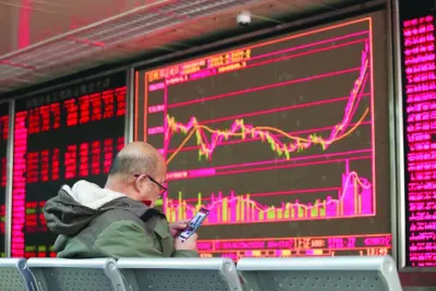 An investor looks at his mobile phone in front of a board showing stock information at a brokerage office in Beijing. A 2023 survey of 100 pension and sovereign wealth managers by London-based think-tank Official Monetary and Financial Institutions Forum found none of them have a positive outlook on China, or see higher relative returns.