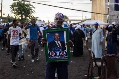 TOPSHOT - A supporter of incumbent Comoros President and presidential candidate for the Convention for the Renewal of the Comoros (CRC) party, Azali Assoumani, poses for a picture while holding a portrait of Assoumani during the last rally ahead of the presidential elections in Moroni, on January 12, 2024. Voters in the Comoros choose a new president on January 14, 2024 with incumbent Azali Assoumani, who has already extended his time in office through constitutional change, voicing confidence of winning a third consecutive term against a divided opposition. (Photo by OLYMPIA DE MAISMONT / AFP)