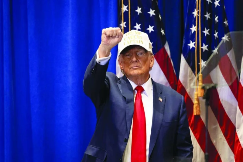 Donald Trump raises his fist at a &#039;Commit to Caucus&#039; event at Simpson College in Indianola, Iowa.