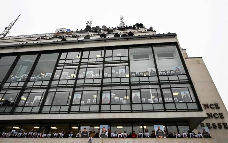 Agence France Presse employees pose on the balconies and in front of windows of the agency&#039;s headquarters in Paris, Wednesday, holding portraits in support of AFP journalists working in Gaza. 