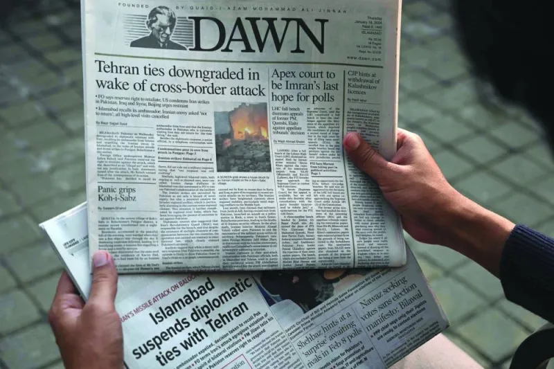 A man in Islamabad reads the front page of the English-language newspaper Dawn displaying news on Iran’s air strike.
