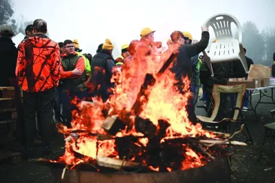 Farmers of the CR47 union, next to a fire, attend a blocking of the A62 highway near Agen, southwestern France, on Saturday, as part of a nationwide movement of protests called by several farmers’ unions on pay, tax and regulations. (AFP)