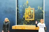 
Two environmental activists from the collective dubbed “Riposte Alimentaire” (Food Retaliation) gesturing as they stand in front of Leonardo Da Vinci’s “Mona Lisa” (La Joconde) painting after hurling soup at the artwork at the Louvre museum in Paris yesterday. (AFP) 