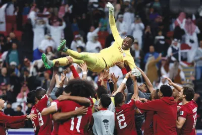Qatar’s players lift their teammate goalkeeper Meshaal Barsham after winning the AFC Asian Cup 2023 quarter-final against Uzbekistan at Al Bayt Stadium in Al Khor on Saturday. (AFP)