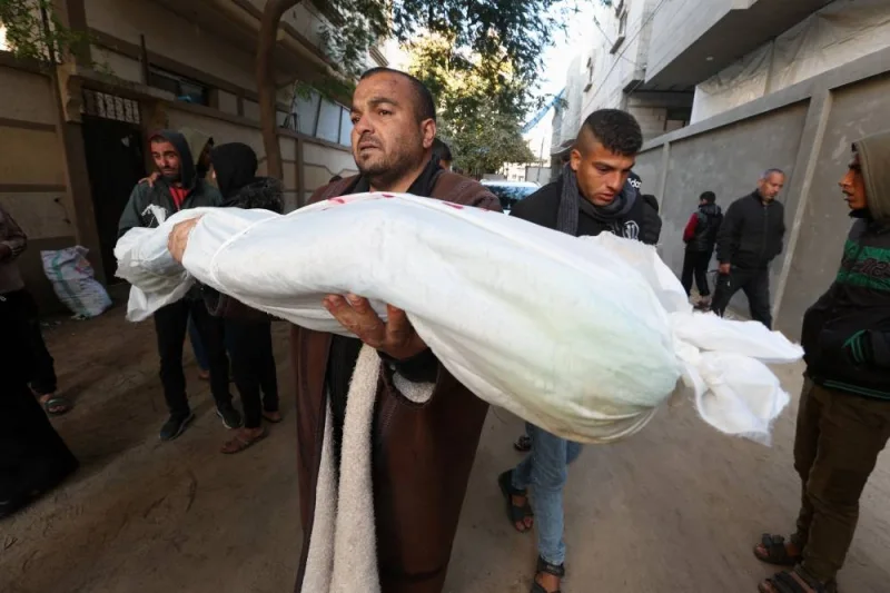 A mourner carries the body of a Palestinian child killed in Israeli strikes in Rafah on Sunday. REUTERS