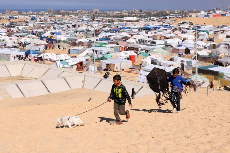 Children walk with a dog, as displaced Palestinians, who fled their houses due to Israeli strikes, take shelter in a tent camp in Rafah. REUTERS