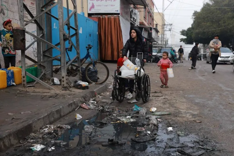 A child transports empty bottles on a wheelchair in Rafah on Friday. AFP