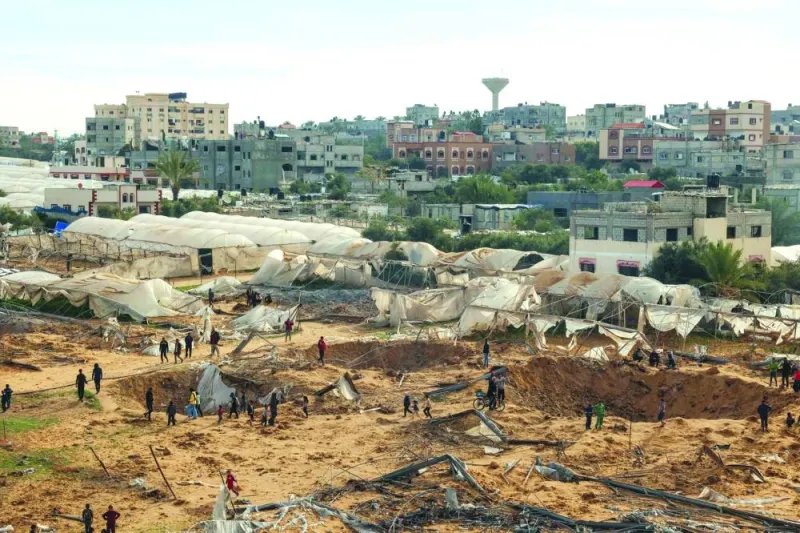 People stand around craters caused by Israeli bombardment in Rafah Monday.