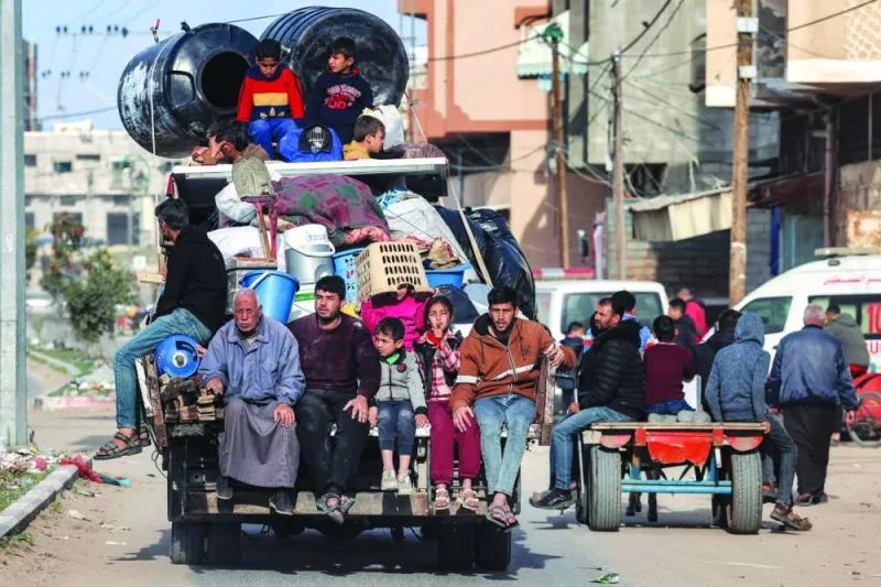 Members of a Palestinian family ride in the back of a truck with belongings as they flee Rafah, taking the coastal road north towards the central Gaza Strip Monday.
