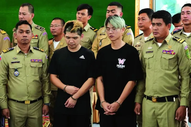 
Taiwanese men Chen Neng-Chuan (centre left) and Lu Tsu-hsin stand with police during a press conference in Preah Sihanouk province, Cambodia, after they were arrested for streaming video of a fake kidnapping. 