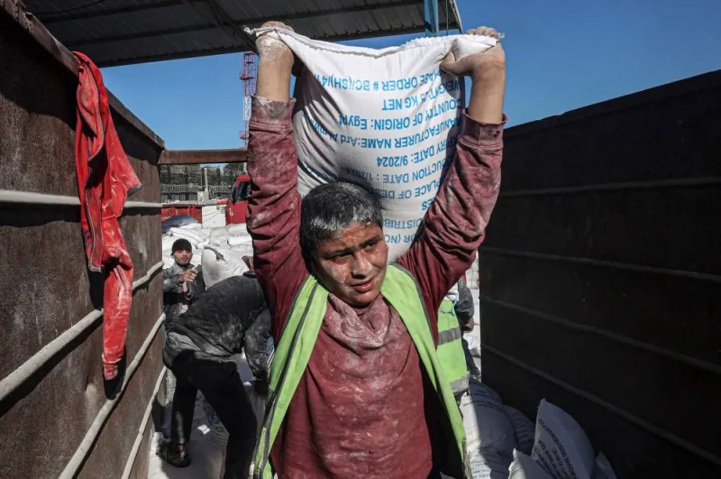Workers unload bags of humanitarian aid that entered Gaza by truck through the Kerem Shalom (Karm Abu Salem) border crossing in the southern part of the Palestinian territory on Saturday, in Rafah on the southern Gaza Strip. AFP