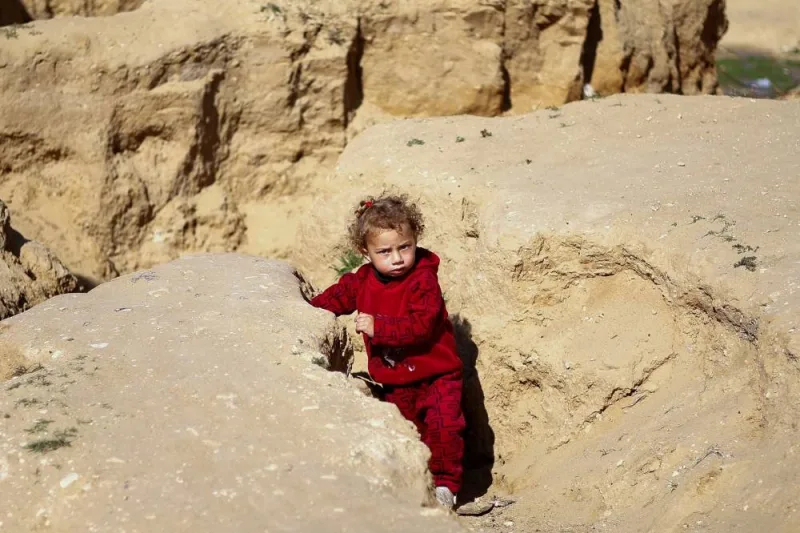 A displaced Palestinian child, who fled due to Israeli strikes, stands between rocks in Rafah in the southern Gaza Strip, on Tuesday. REUTERS