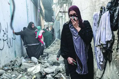 People find their way through a rubble-covered alley, following overnight Israeli bombardment in Rafah, Sunday.