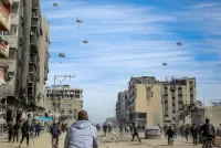 Palestinians run along a street as humanitarian aid is airdropped in Gaza City on Friday. AFP