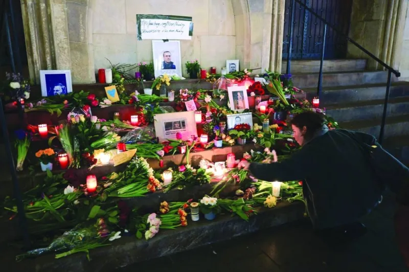 
A woman lays down a candle at a makeshift memorial of flowers and candles for Navalny in front of the city hall in Muenster, western Germany. 