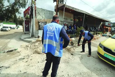 
United Nations Relief and Works Agency for Palestine Refugees (UNRWA) employees clear a damaged street following an Israeli raid in the Nur Shams camp near Tulkarem in occupied West Bank, yesterday. 