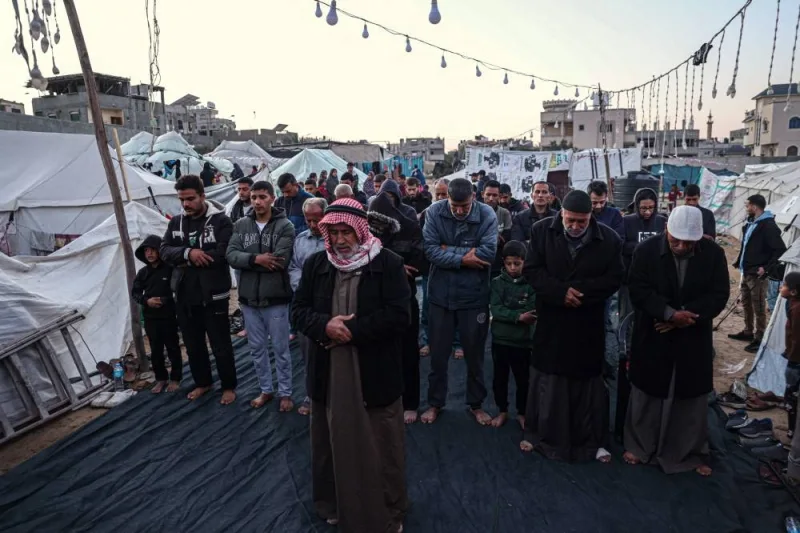 Palestinians pray before breaking the fast on the first day of the Muslim holy fasting month of Ramadan, at a camp for displaced people in Rafah in the southern Gaza Strip, on Monday. AFP
