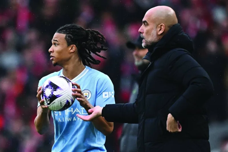 
Manchester City manager Pep Guardiola (right) passes a stray ball to City’s defender Nathan Ake for a throw in during the English Premier League match against Liverpool at Anfield in Liverpool on Sunday. (AFP) 
