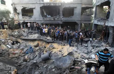 Palestinians gather around a destroyed home of the al-Dallu family following an Israeli air strike in Gaza City, on November 18, 2012.  At least seven members of the same family, including four children, were among nine people killed when an Israeli missile struck a family home in Gaza City, the health ministry said.  AFP PHOTO/MAHMUD HAMS        (Photo credit should read MAHMUD HAMS/AFP/Getty Images)