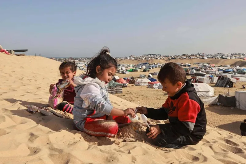 Palestinian children play on a sand dune overlooking a camp for displaced people in Rafah in the southern Gaza Strip on Sunday. AFP