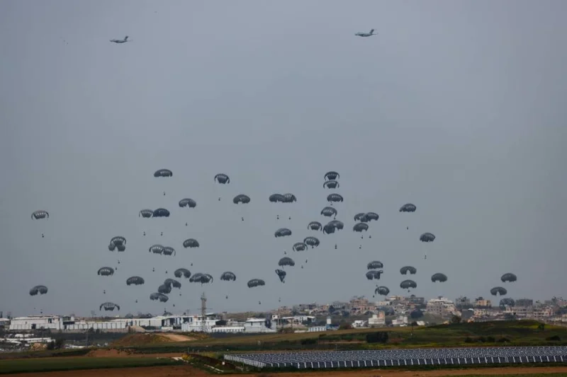 Humanitarian aid falls through the sky towards the Gaza Strip after being dropped from an aircraft as seen from Israel&#039;s border with Gaza, in southern Israel, on Sunday. REUTERS
