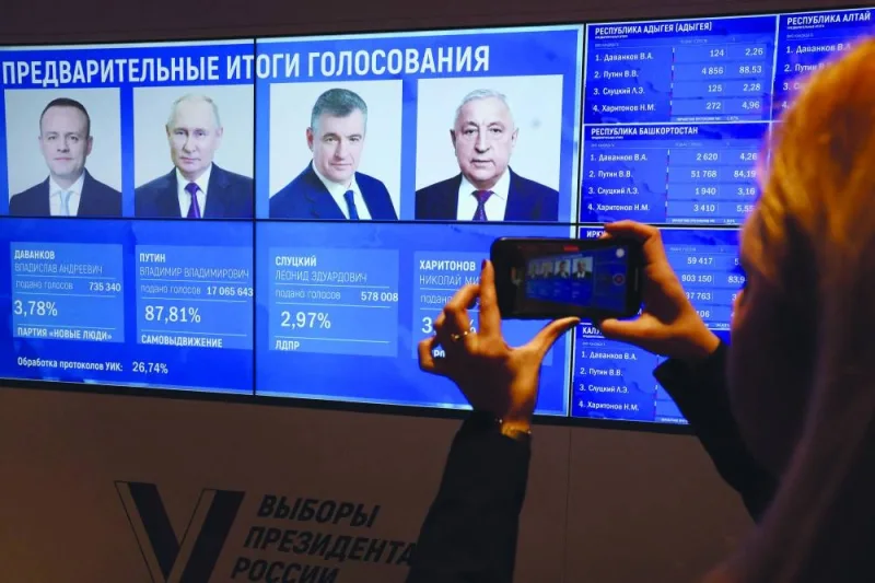 
A woman takes a photograph with her mobile telephone of a screen with preliminary voting results in the Russian presidential election at the Central Election Commission in Moscow yesterday. (AFP) 