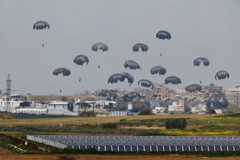 Humanitarian aid falls through the sky towards the Gaza Strip after being dropped from an aircraft, as seen from Israel&#039;s border with Gaza, in southern Israel, on Sunday. REUTERS