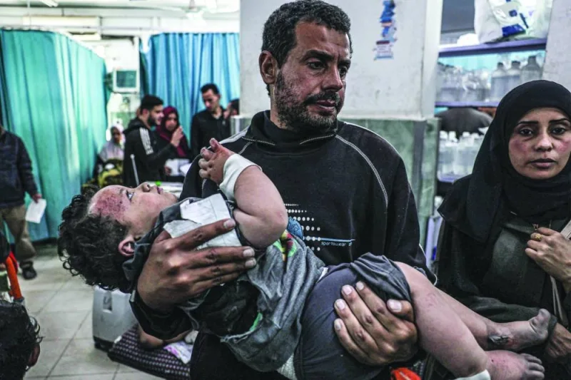 A man carries a child, who was injured in an Israeli air strike on a building, at the Al-Najjar hospital in Rafah Wednesday. 