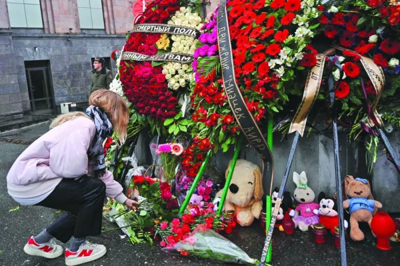A woman lays flowers at a makeshift memorial in front of the Russian embassy in Yerevan Saturday.