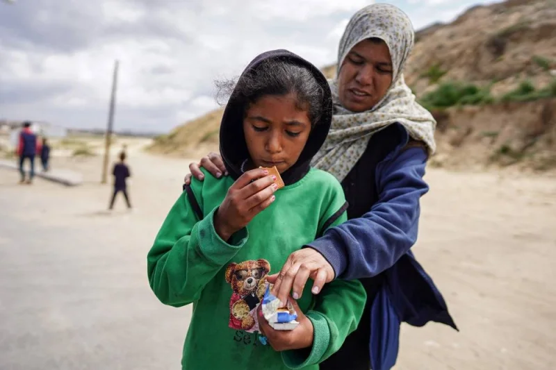 A girl eats biscuits as a woman behind her reaches for the pack as they evacuate from Gaza City on Monday. AFP