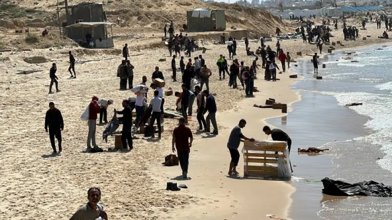 Palestinians gather on a beach as they collect aid airdropped by an airplane in the northern Gaza Strip, on Monday. REUTERS